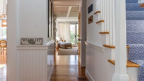 A hallway with a wooden floor, white walls, and a staircase with patterned fabric. - 600 Feet to Private Association Cape Cod Bay Beach (2266) (Eastham)