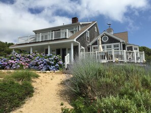 A large, two-story house with a covered porch and a fenced deck.