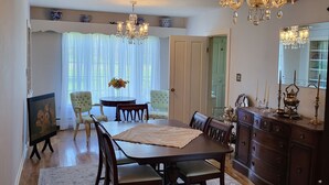 Un comedor con mesa de madera, sillas, una araña y un espejo grande.