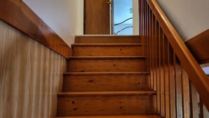 Una escalera de madera con barandilla que lleva a una puerta.