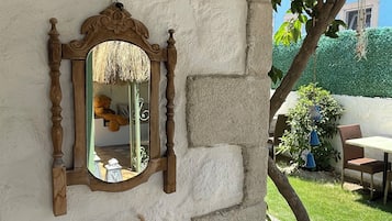 Un mur de pierres apparentes, agrémenté d’un miroir encadré en bois, d’un panier tressé et de plantes séchées.