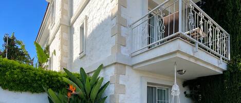 A two-story building with a balcony, outdoor seating, and a well-maintained lawn.
