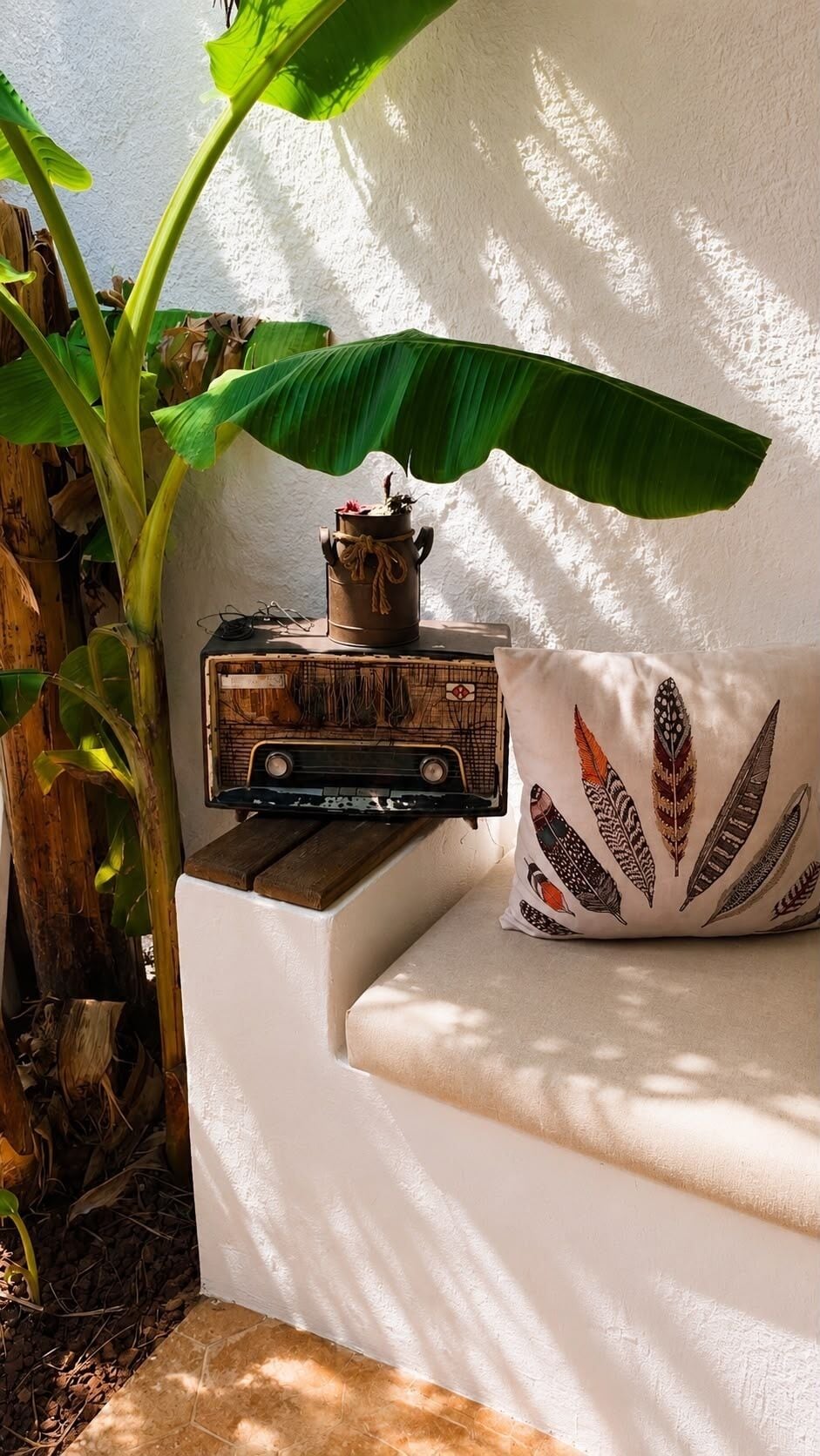 A white sofa with a decorative pillow, a vintage radio, and a potted plant.