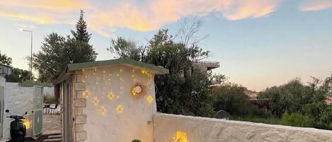 Une terrasse sur le toit, avec un espace salon, une petite table et une lanterne.