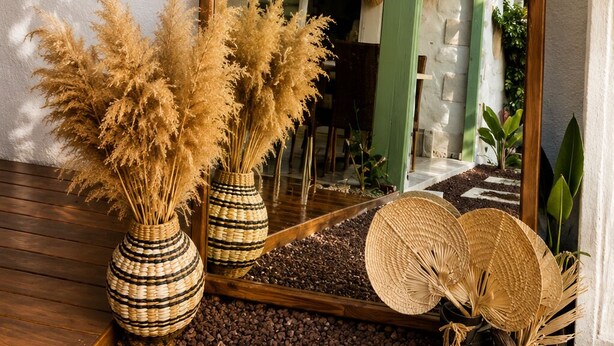 A mirror with a wooden frame, a wooden bench, and two woven vases with pampas grass. - Casa De Vien (Cesme)