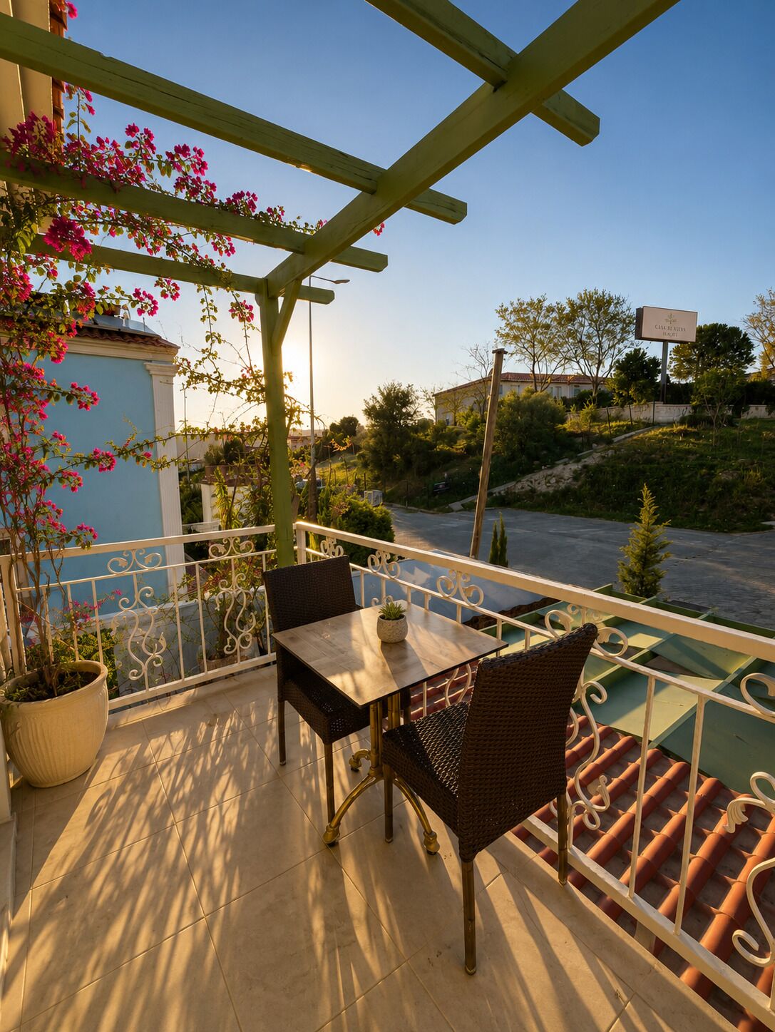 A balcony with a table and chairs, a pergola, and a view of the surrounding area.