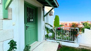 A house with a green door, a small porch, and a garden with white pebbles and plants. - Casa De Vien (Cesme)