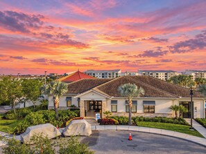 A hotel with a red roof, surrounded by greenery and palm trees, with a view of the sunset. - Sunny Family Escape/ Private Pool & Themed Rooms (Kissimmee)
