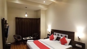 A hotel room with a large bed, a desk, a chair, and a TV. - Hotel Popular (Pune)
