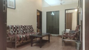 A living room with a sofa, a coffee table, and a chair. - Hotel Popular (Pune)