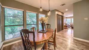 A dining area with a wooden table, chairs, and pendant lights.