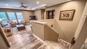 A spacious living area with a staircase, a flat-screen TV, and a bookshelf.