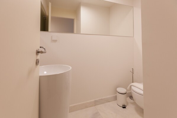 A modern bathroom with a white sink, toilet, and mirror.