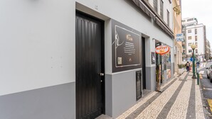 Une façade d’immeuble avec une porte noire, une enseigne indiquant un buffet, et une vue de la rue avec un piéton.