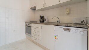 Une cuisine avec des meubles blancs, une machine à café, un grille-pain et un lave-vaisselle.