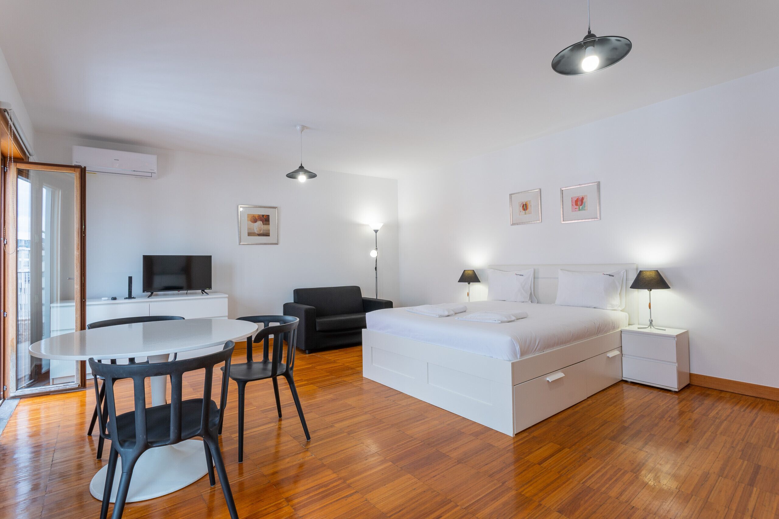 Un dormitorio moderno con cama, mesitas de noche, un escritorio y sillas.