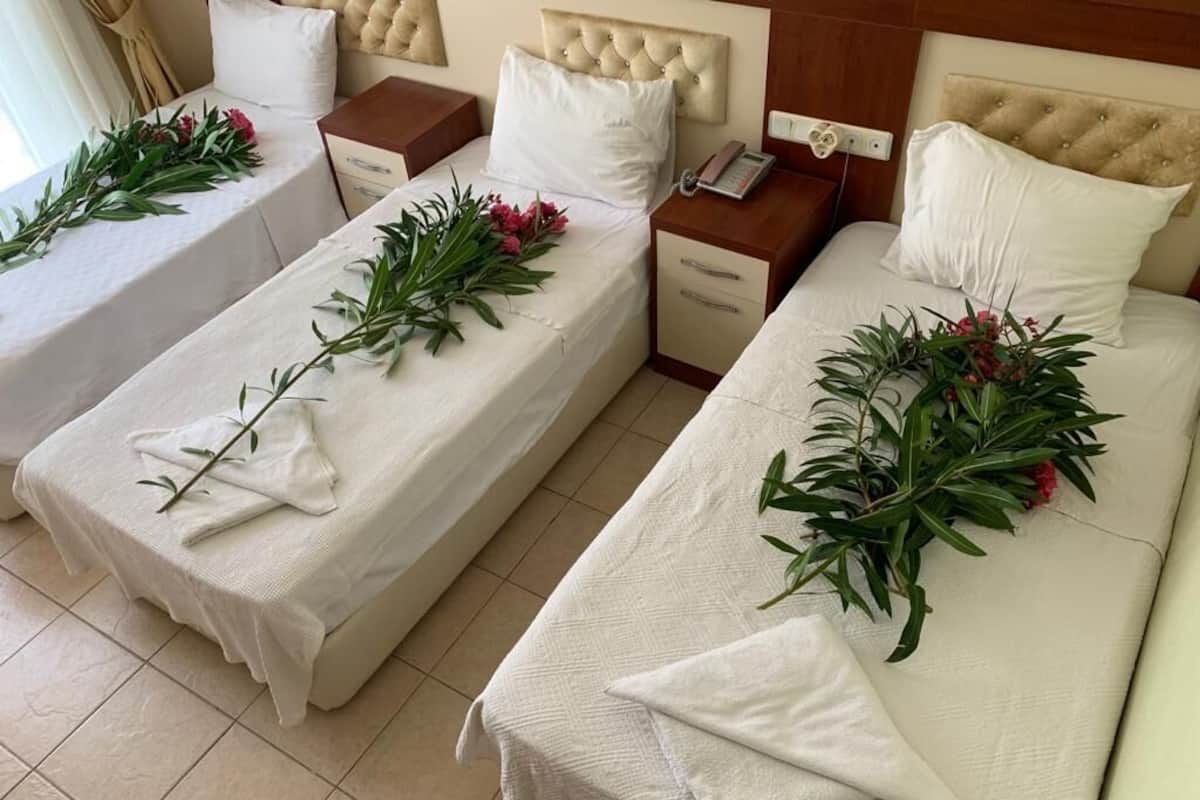 Two single beds with white linens, each adorned with a branch of greenery and pink flowers.