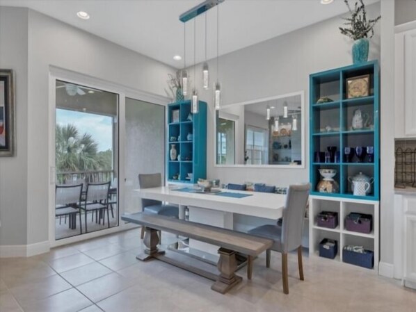 A modern dining area with a white table, blue shelving, and a bench.