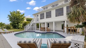 Ein zweistöckiges Haus mit Schwimmbad, Gartenmöbeln und einer überdachten Terrasse.