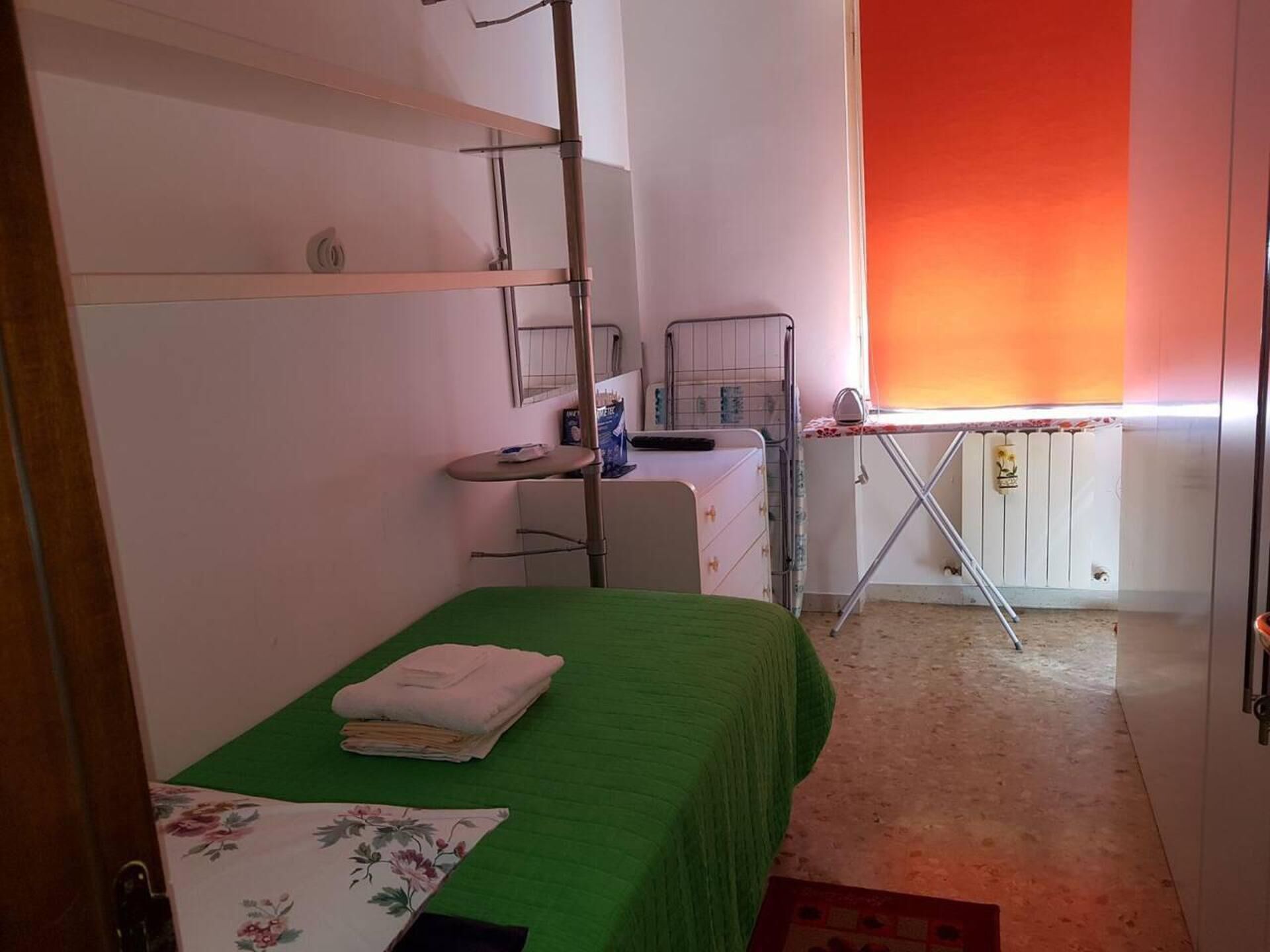 A small, compact room with a single bed, a desk, and a radiator.