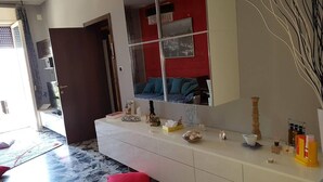 Une salle de bain moderne avec un grand miroir, un meuble-lavabo blanc et un mur d’accent rouge.