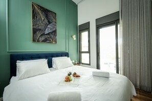 A neatly made bed with white linens, a laptop, and breakfast items on the bedside table.