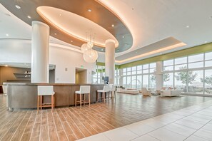 A spacious lobby with a central bar area, large windows, and a modern design.