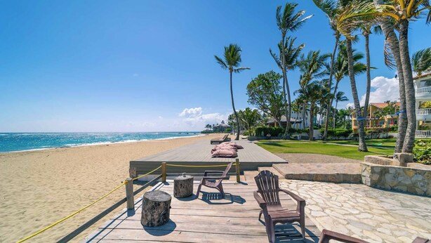 A wooden deck with a table and chairs overlooking a beach.