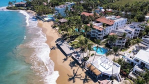 A coastal resort with beachfront villas, a swimming pool, and palm trees.