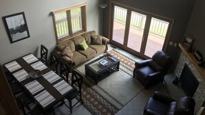 A living room with a sofa, coffee table, and chairs, a dining area with a table and chairs, and a fireplace. - Ski and Golf Retreat by Hole 8 (Clymer)