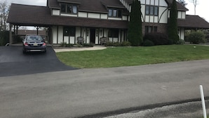 A two-story house with a covered porch and a car parked in the driveway. - Ski and Golf Retreat by Hole 8 (Clymer)