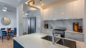 A modern kitchen with a central island, stainless steel appliances, and a dining area with blue chairs.