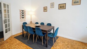 A dining area with a wooden table, blue chairs, and a patterned wall hanging. - A break somewhere! (Marseille)