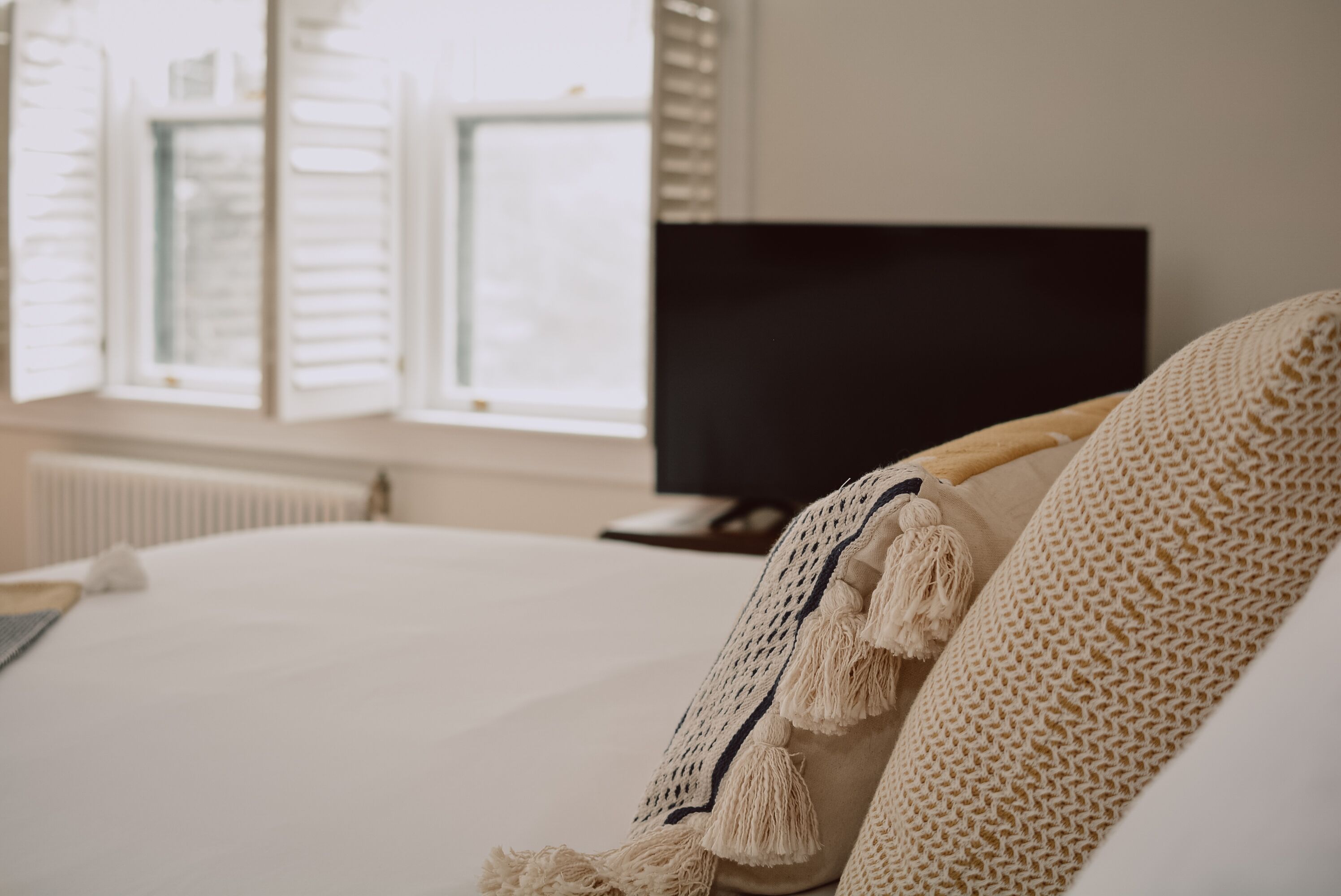 A bedroom with a bed, a television, and a window with blinds.
