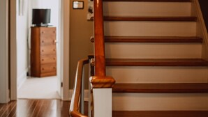 Eine Holztreppe mit Handlauf, die zu einem Raum mit Holzboden und einem Schminktisch führt.