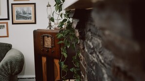 Ein altes Radio, ein grüner Sessel und eine Wand mit gerahmten Bildern.