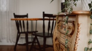 Ein Holztisch mit Stühlen, eine Holzkommode mit Schubladen und eine Pflanze mit grünen Blättern.