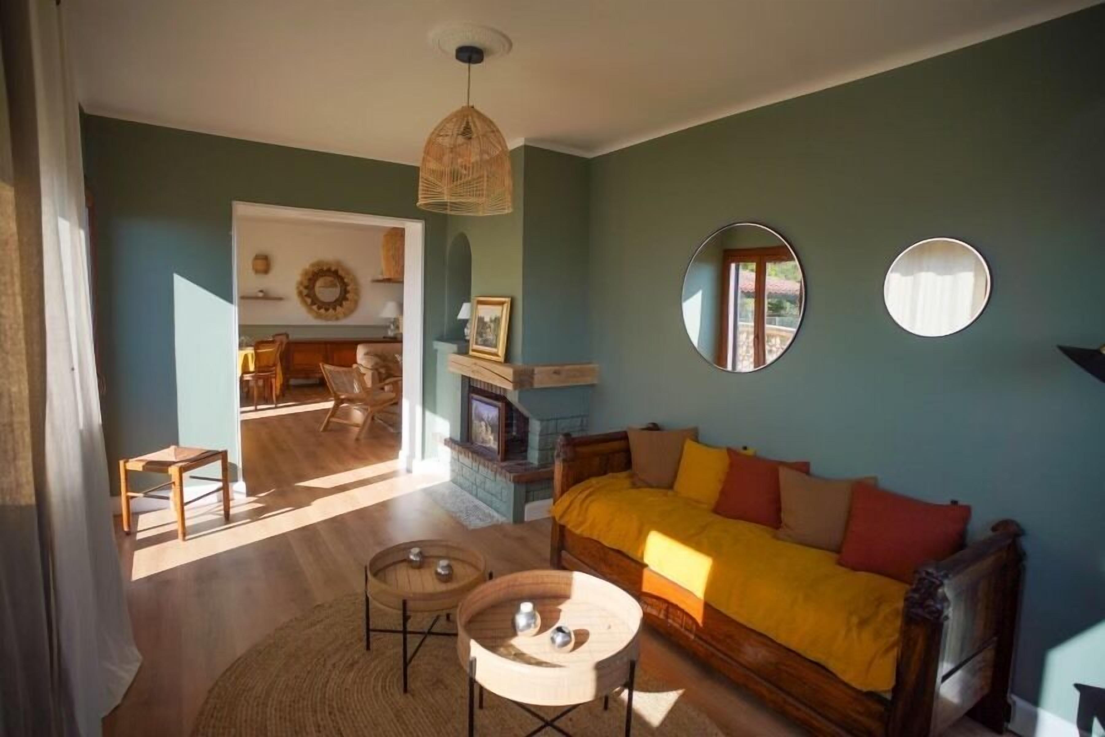 A cozy living room with a wooden sofa, two round tables, and a fireplace.
