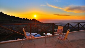 Vista al atardecer desde un balcón con dos sillas y una mesa.