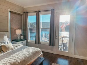 Relax in this serene bedroom with a large bed, nightstand, and sliding glass door leading to an outdoor area with a water view.