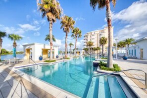 Una piscina con palmeras y un edificio al fondo.