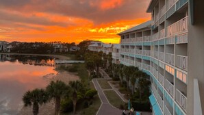 Ein Hotel mit mehreren Etagen, einem Swimmingpool und Blick auf den Sonnenuntergang.