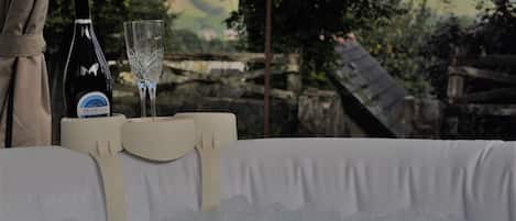 A bottle of Prosecco and a glass on a table with a white tablecloth, set against a scenic outdoor backdrop.
