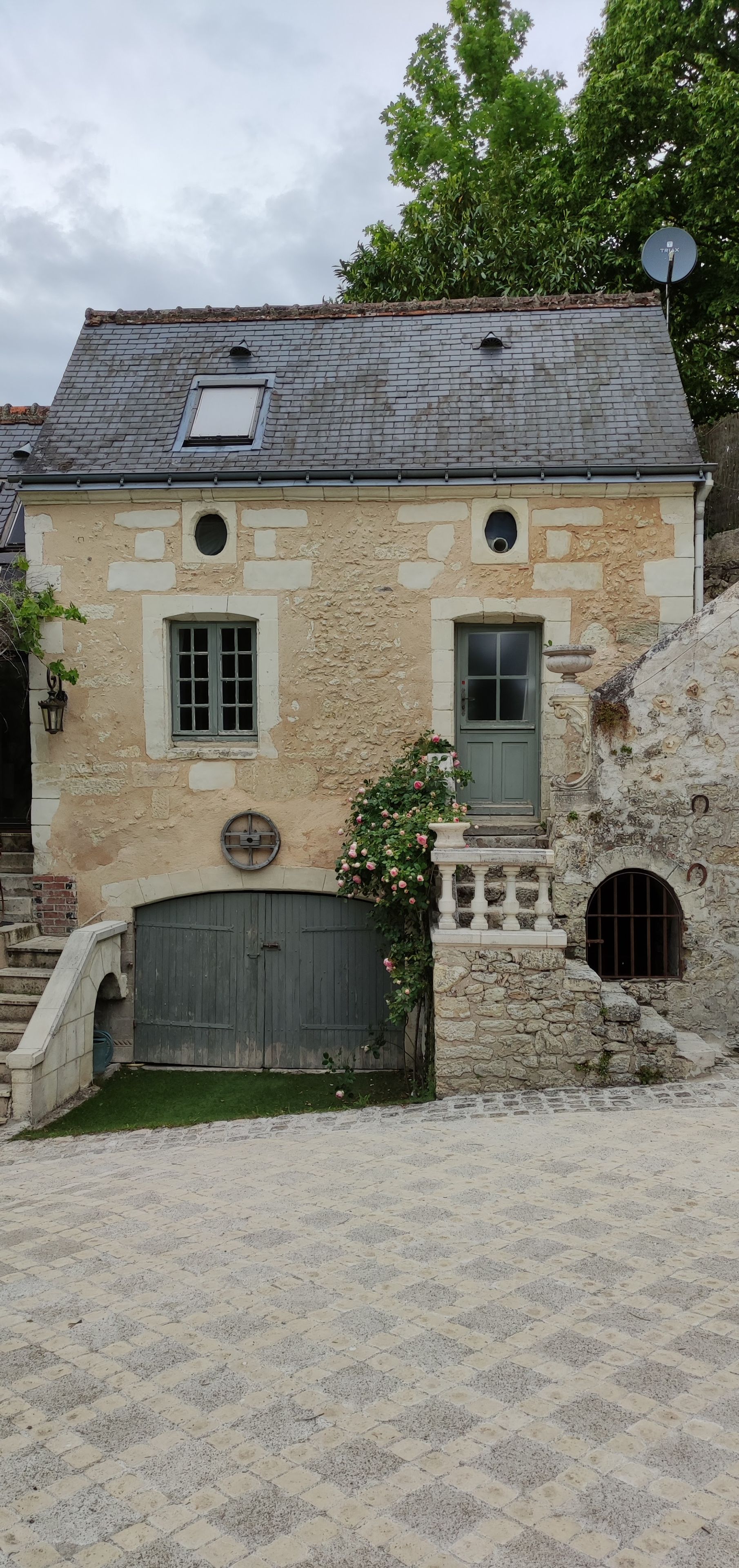 A stone building with a grey door, a small window, and a satellite dish.