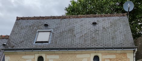 Un edificio de piedra con una puerta gris, una ventana pequeña y una antena parabólica.