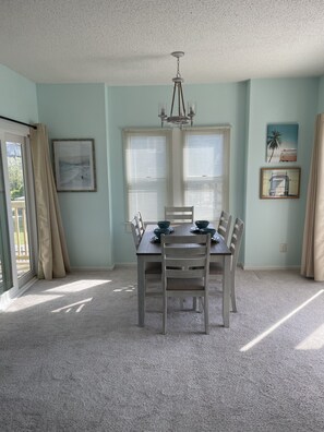 A dining room with a wooden table and chairs, a chandelier, and artwork on the walls.