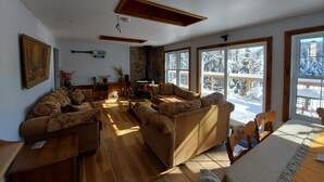 Una sala de estar acogedora con chimenea, ventanas amplias y una pared de piedra.