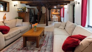 A living room with a wooden coffee table, two sofas, a patterned rug, and a staircase leading to a kitchen. - Charming Guest House in Cornish countryside - Demelza Cottage (BODMIN)