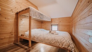 Un lit superposé en bois, surmonté d’une petite fenêtre et agrémenté d’une couverture à motifs géométriques.