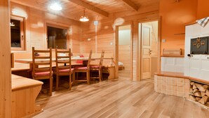 Un intérieur en bois comprenant une table et des chaises, un coin cuisine et une cheminée.